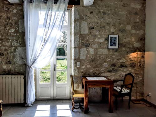 Cette chambre ancienne dispose d'une table et d'une fenêtre. dans l'établissement Gîte Kiwi - Domaine du Pi geonnier de Saint-Vincent, à Bourran
