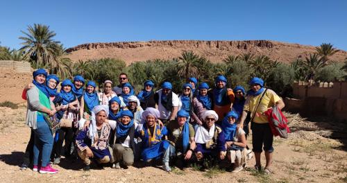 a group of people posing for a picture in the desert at Gite Tamlli in Aoufous