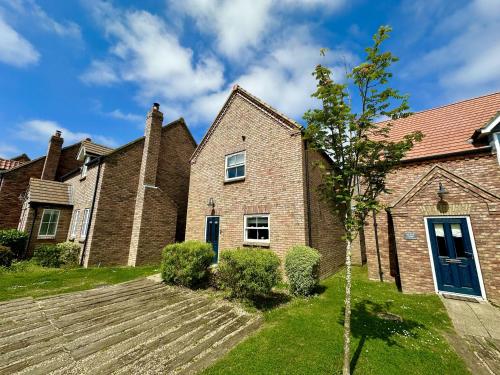 ein altes Backsteinhaus mit einer blauen Tür in der Unterkunft Baybreak - Part of the The Bay Filey Holiday Village with pool, gym and direct beach access, pub, restaurant, tennis and meadows walks in Filey