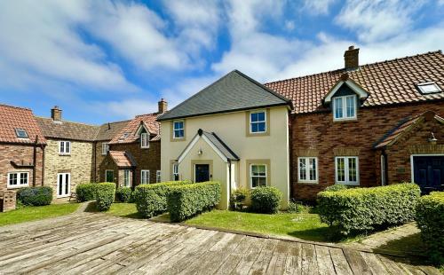 a large brick house with a wooden driveway at Coral Shores - Part of the The Bay Filey Holiday Village with pool, gym and direct beach access, pub, restaurant, tennis and meadows walks in Filey