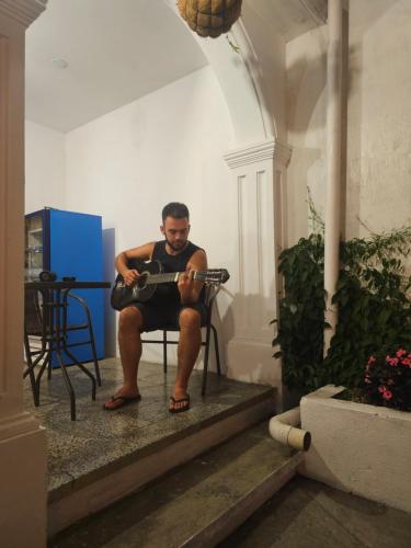a man sitting in a chair playing a guitar at Blue Moon Hostel in Antigua Guatemala