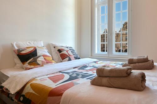 ein Schlafzimmer mit einem Bett mit Kissen und einem Fenster in der Unterkunft Le Art Déco in Arras