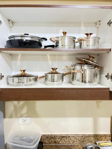 a shelf full of pots and pans in a kitchen at Two Bedroom Condo in Fairview in Manila