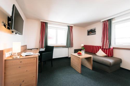a hotel room with a couch and a desk and window at Hotel Tradizio in Mittelberg