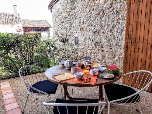 a wooden table with chairs and a table with food on it at Gîte Noisette - Domaine du Pi geonnier de Saint-Vincent in Bourran