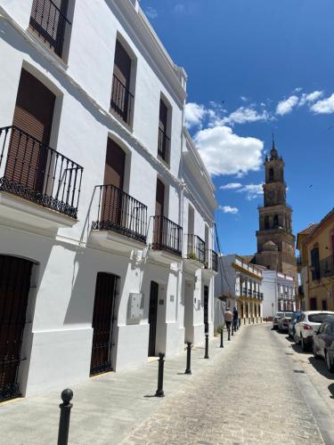 une rue avec des bâtiments blancs et une tour d'horloge dans l'établissement Apartamento Puerta del Perdón, à Constantina