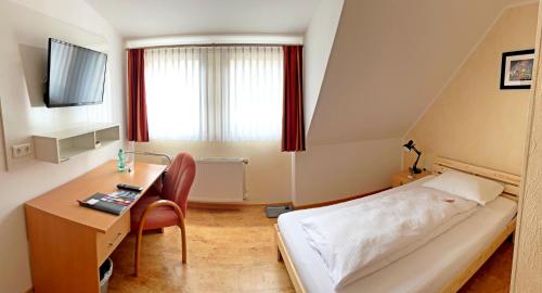 Habitación pequeña con cama, escritorio y TV. en Hotel zur Loreley - Garni en Sankt Goar