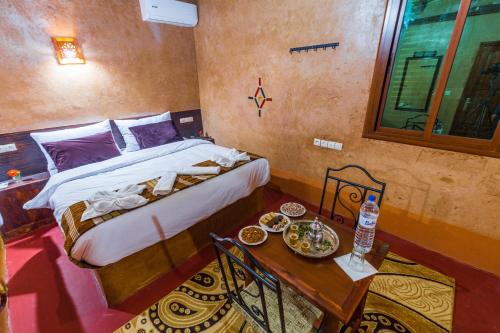 a bedroom with a bed and a table with food on it at Palais Ksar Lamane in Aït Ben Haddou