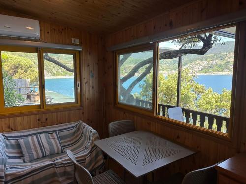 Cette chambre dispose de deux fenêtres, d'une table et de chaises. dans l'établissement Villaggio Smeraldo, à Moneglia