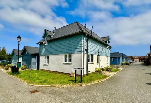 a blue and white house with a street sign in front at New England Cottage - Part of the The Bay Filey Holiday Village with pool, gym and direct beach access, pub, restaurant, tennis and meadows walks in Filey
