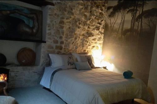 a bedroom with a white bed with a stone wall at La chiave del Tempo in Casteldilago