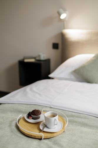 a tray with a cup of coffee and a muffin on a bed at River Apartments in Mladá Boleslav