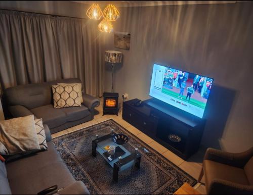 ein Wohnzimmer mit einem Sofa und einem Flachbild-TV in der Unterkunft Motebong Villa in Maseru