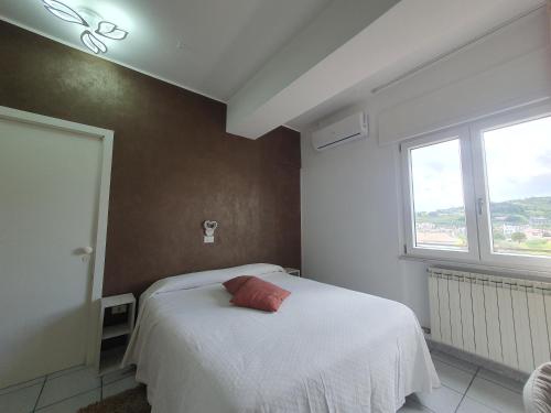 1 dormitorio con cama blanca y almohada roja en Hotel Ristorante Supersonik, en Acri