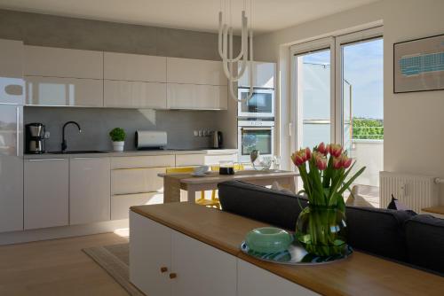 a kitchen with white cabinets and a vase of flowers on a table at Apartament z tarasem Panorama in Kołobrzeg