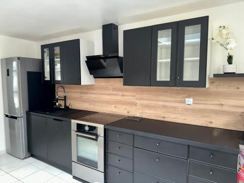 une cuisine avec des armoires noires et un comptoir en bois dans l'établissement Appartement à 50m de la plage, à Saint-Hilaire-de-Riez