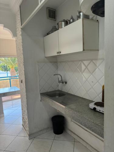 - une cuisine avec des placards blancs et un évier dans l'établissement Hôtel Résidence Louban, à Agadir