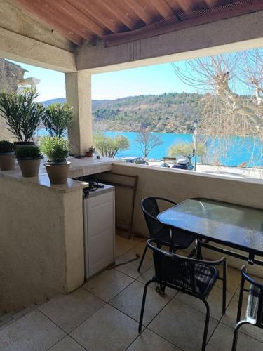 a patio with a table and chairs and a view of the water at L'Alorenlis, duplex vue lac de Sainte Croix in Bauduen