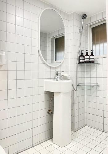 a white tiled bathroom with a sink and a mirror at 갓성비 암사역 도보 Yes24live 암사종합시장 한강공원 KSPO 2룸 2퀸 침대 in Seoul