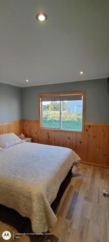 Un dormitorio con una cama grande y una ventana en Cabaña Puyehue, en Puyehue