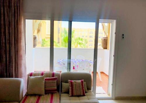 een woonkamer met een bank voor een groot raam bij appart très luxueux 6 personnes in El Ahmar