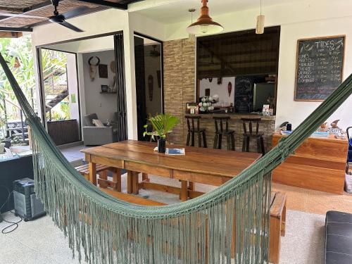 a hammock in a restaurant with a table and a bar at El Chante Surf House in Santa Teresa Beach
