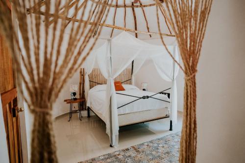 a bedroom with a white bed with a canopy at HACIENDA SANTO DOMINGO DE YUNKU in Yuncu