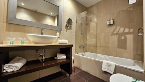uma casa de banho com um lavatório, uma banheira e um espelho. em Las Bóvedas em Badajoz