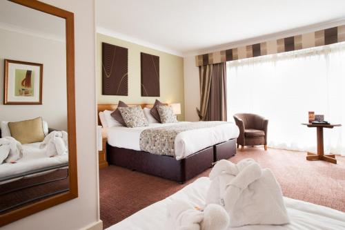 a hotel room with two beds and a mirror at Abbey Hotel Golf & Spa in Redditch