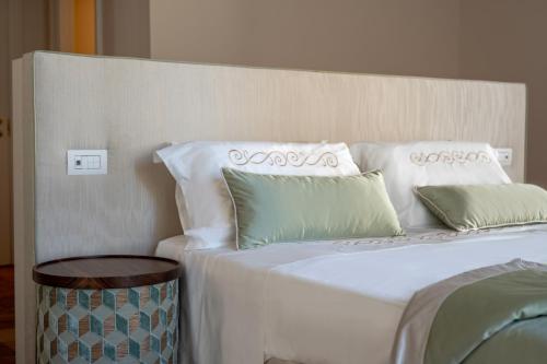 a bed with white sheets and green pillows at Aqua Mirabilis Relais de Charme in Minori