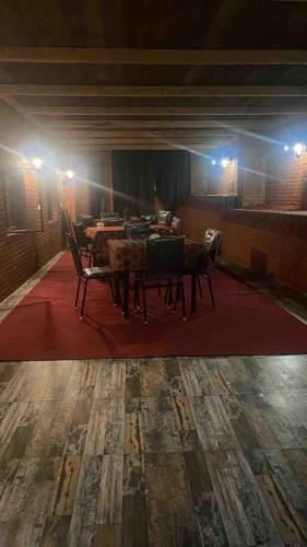 a dining room with tables and chairs on a red rug at My Family hotel in Tbilisi City