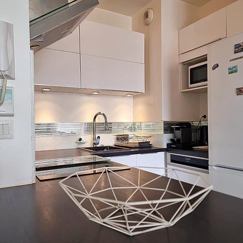 une cuisine avec des armoires blanches et un évier dans l'établissement T2 Paris Disneyland Balcon Parking, à Noisy-le-Grand