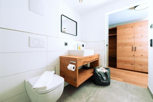 a bathroom with a white toilet and a wooden cabinet at Hotel Tradizio in Mittelberg