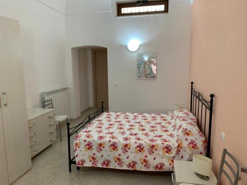 a bedroom with a bed with a floral bedspread and a dresser at Casa sul porto imbarco Tremiti in Termoli