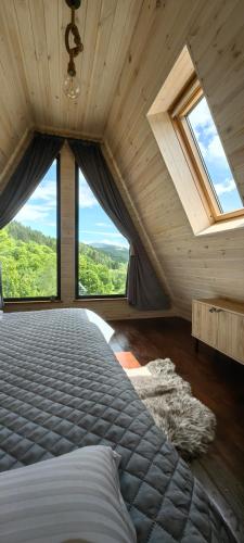 ein Schlafzimmer mit einem Bett und einem großen Fenster in der Unterkunft Păltinel in Braşov