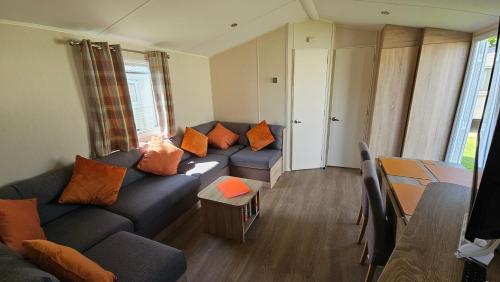 sala de estar con sofá azul y almohadas de color naranja en KP Holiday Home, en Corton