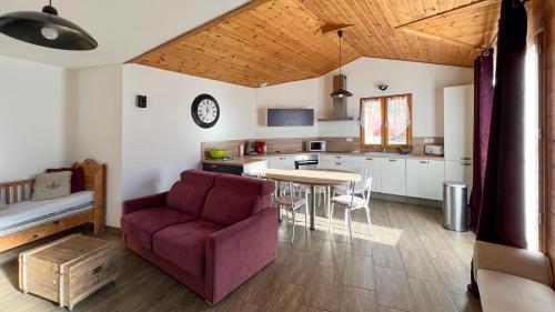 a living room with a purple couch and a kitchen at L'Intermède & En toute amitié - Les Gites de l'Argile in Faucon-de-Barcelonnette