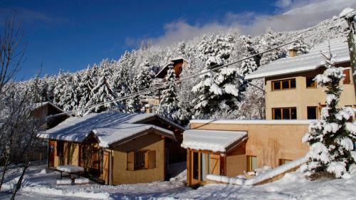 a house covered in snow in front of a mountain at L'Intermède & En toute amitié - Les Gites de l'Argile in Faucon-de-Barcelonnette