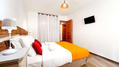 a bedroom with a bed and a desk and a television at L'Intermède & En toute amitié - Les Gites de l'Argile in Faucon-de-Barcelonnette