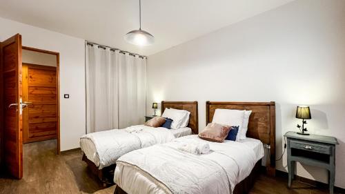 a bedroom with two beds and a night stand with a lamp at L'Intermède & En toute amitié - Les Gites de l'Argile in Faucon-de-Barcelonnette