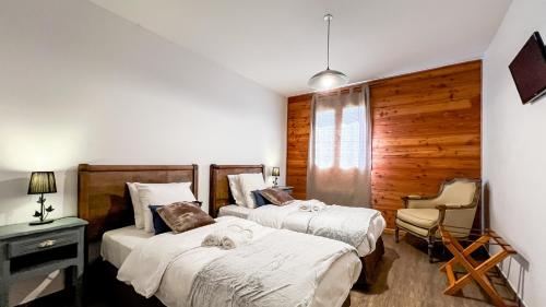 a bedroom with two beds and a chair at L'Intermède & En toute amitié - Les Gites de l'Argile in Faucon-de-Barcelonnette