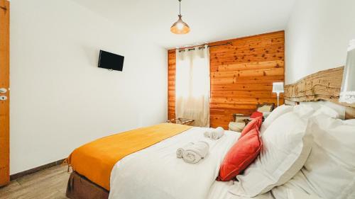 a bedroom with a large bed with red pillows at L'Intermède & En toute amitié - Les Gites de l'Argile in Faucon-de-Barcelonnette