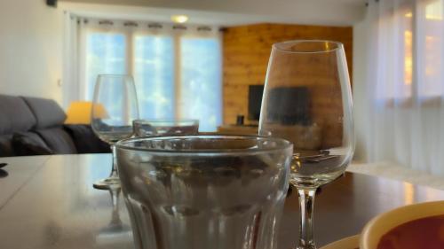 three wine glasses sitting on a wooden table at L'Intermède & En toute amitié - Les Gites de l'Argile in Faucon-de-Barcelonnette