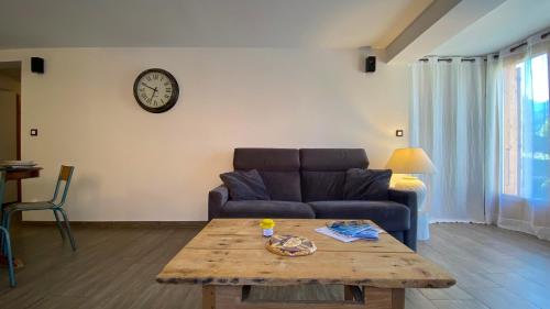 a living room with a couch and a wooden table at L'Intermède & En toute amitié - Les Gites de l'Argile in Faucon-de-Barcelonnette