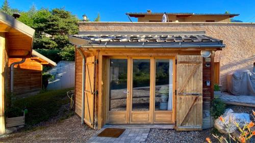 a wooden greenhouse with a roof on top of it at L'Intermède & En toute amitié - Les Gites de l'Argile in Faucon-de-Barcelonnette