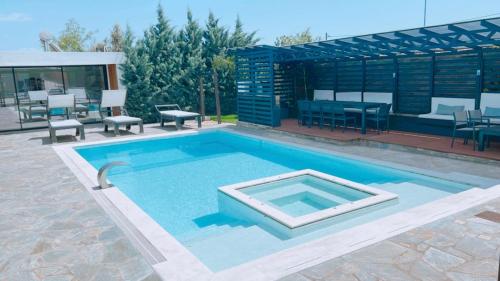 a large swimming pool with chairs and a table at Olivujoj Villajoj - Deluxe Villa with Detached Pool House in Anavissos