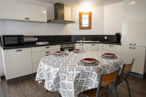 a kitchen with a table with chairs and a microwave at L'Intermède & En toute amitié - Les Gites de l'Argile in Faucon-de-Barcelonnette