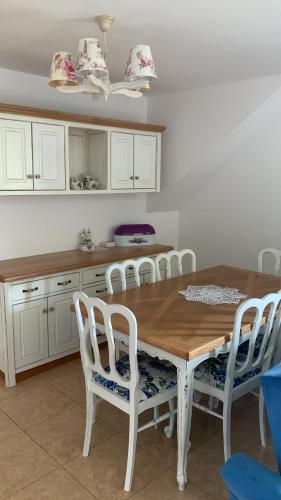 a kitchen with a wooden table and white chairs at zaKRZYWEk wyjątkowy apartament w Krzywe k/Cisnej in Cisna