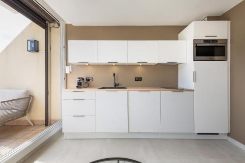 une cuisine avec des armoires blanches et un évier dans l'établissement Free life Heliopolis, au Cap d'Agde