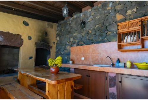 cocina con mesa y pared de piedra en Casa Esteban Y Facunda, en Valverde